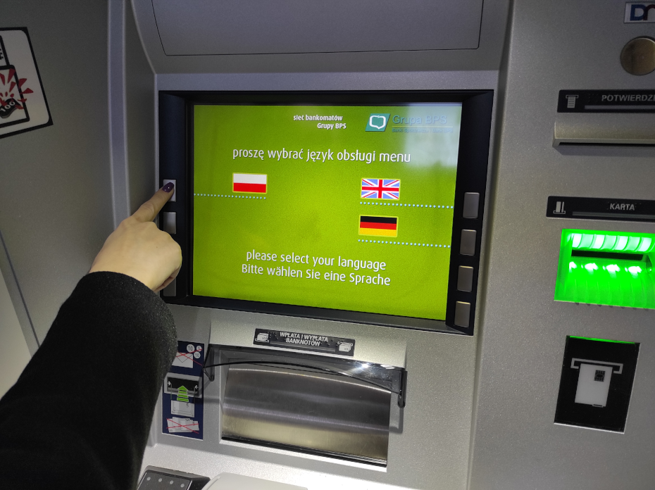 Dłoń wskazująca na przycisk odpowiadający za wybór języka polskiego